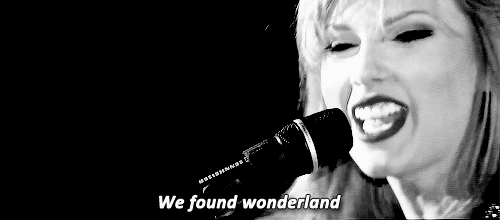 GIF em preto e branco de Taylor cantando "We found wonderland" em um show.
